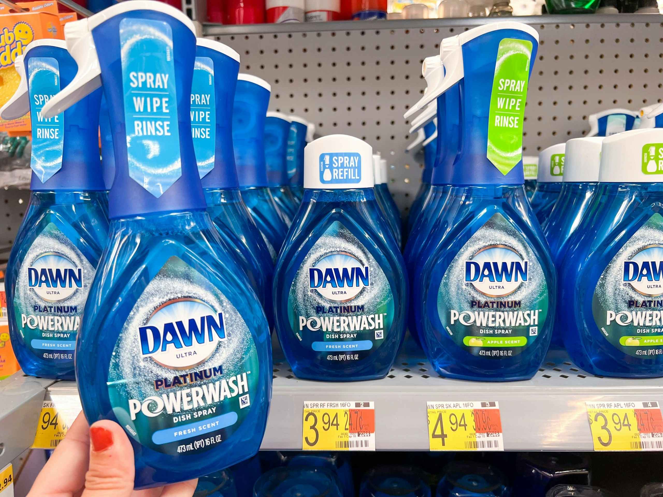 Hand holding a Dawn Power Spray product in front of shelf at Walmart.