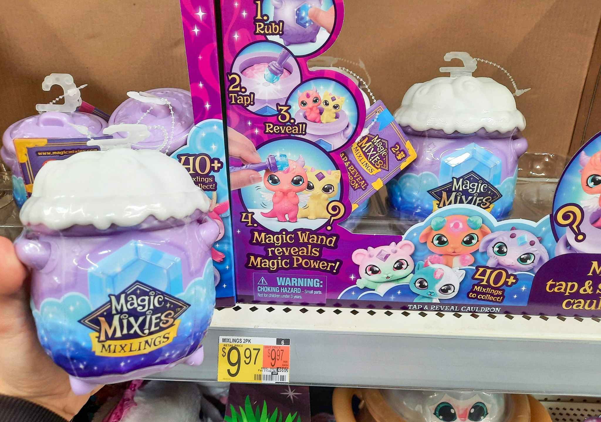 Magic Mixies Mixlings Tap & Reveal Cauldron two pack held in front of shelf at Walmart. Price tag on shelf indicates that the price is $9.97.