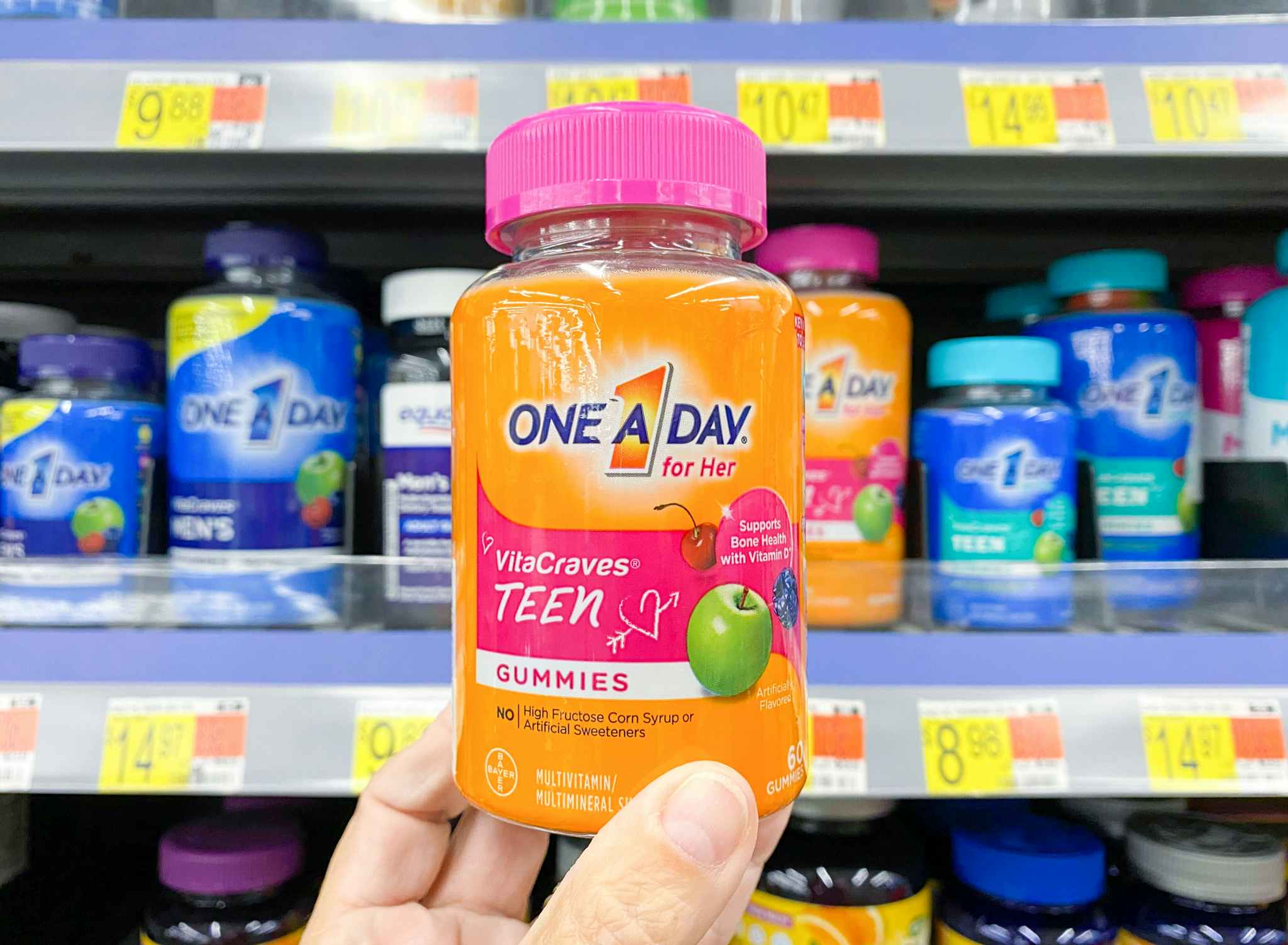 One a Day VitaCraves Teen Gummies held in front of shelf at Walmart