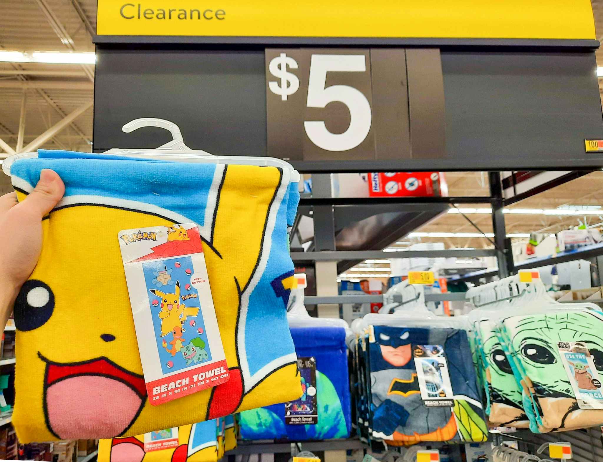 Pokemon Beach Towel held in front of $5 clearance sign.