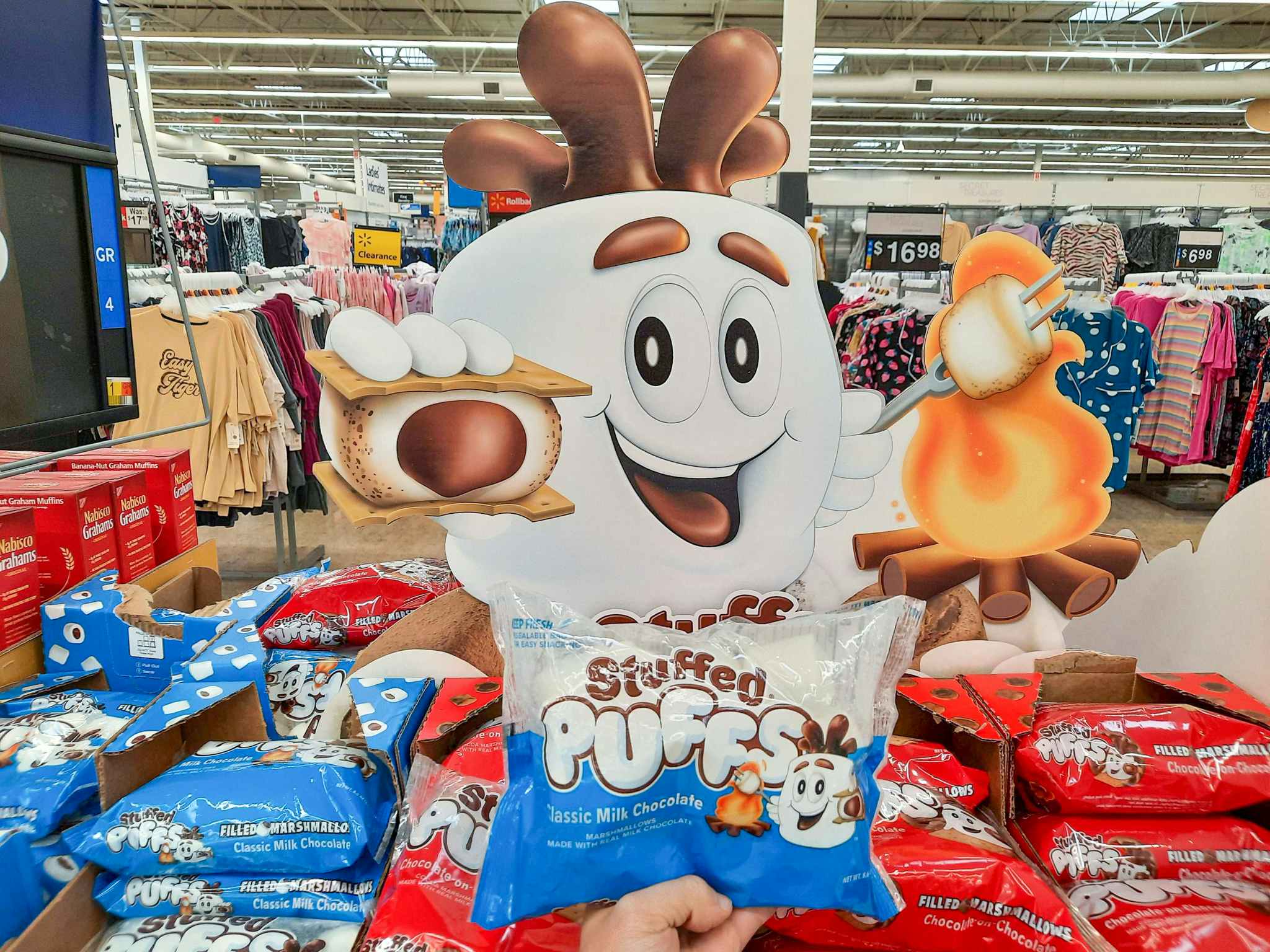 Hand holding a package of Stuffed Puffs Classic Marshmallows in front of display at Walmart