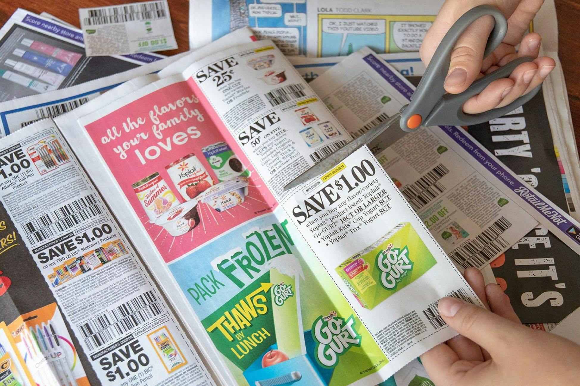 hands with scissors cutting out Go-GURT coupon from newspaper