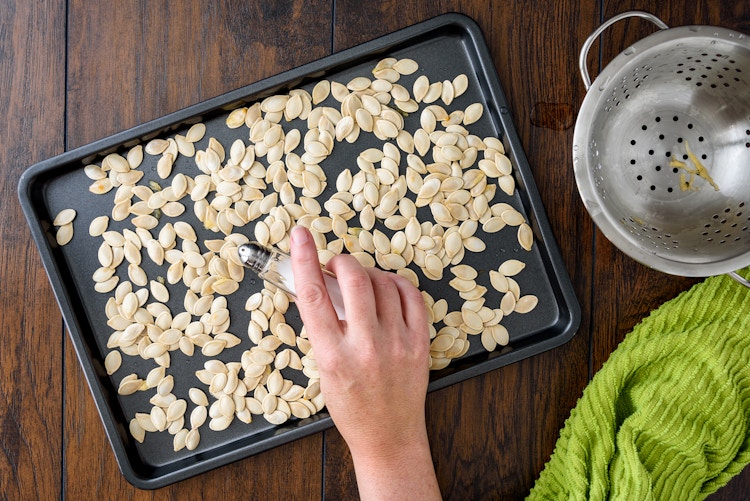 woman salting carved pumpkin seeds in pan