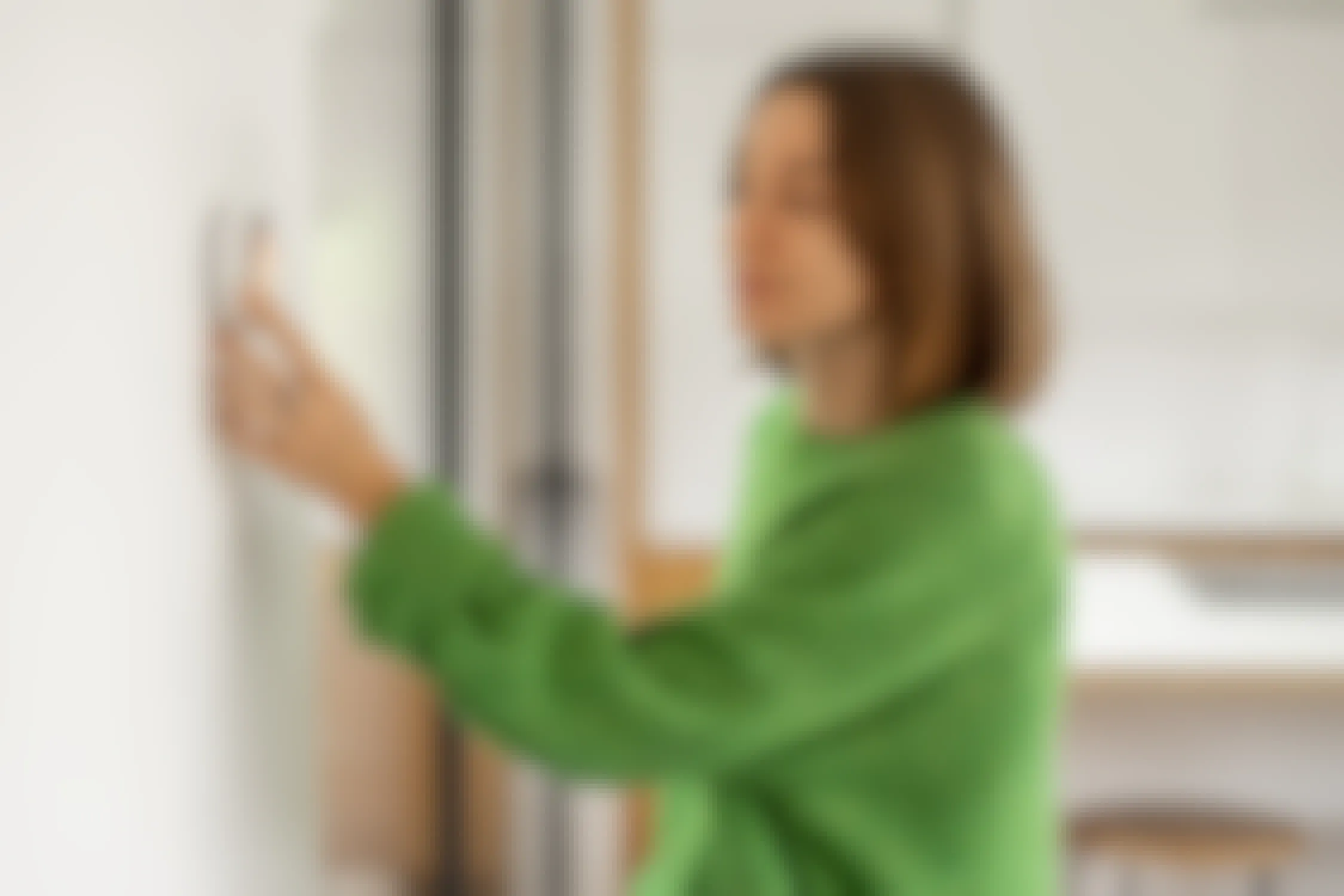 woman adjusting smart wall thermostat in home