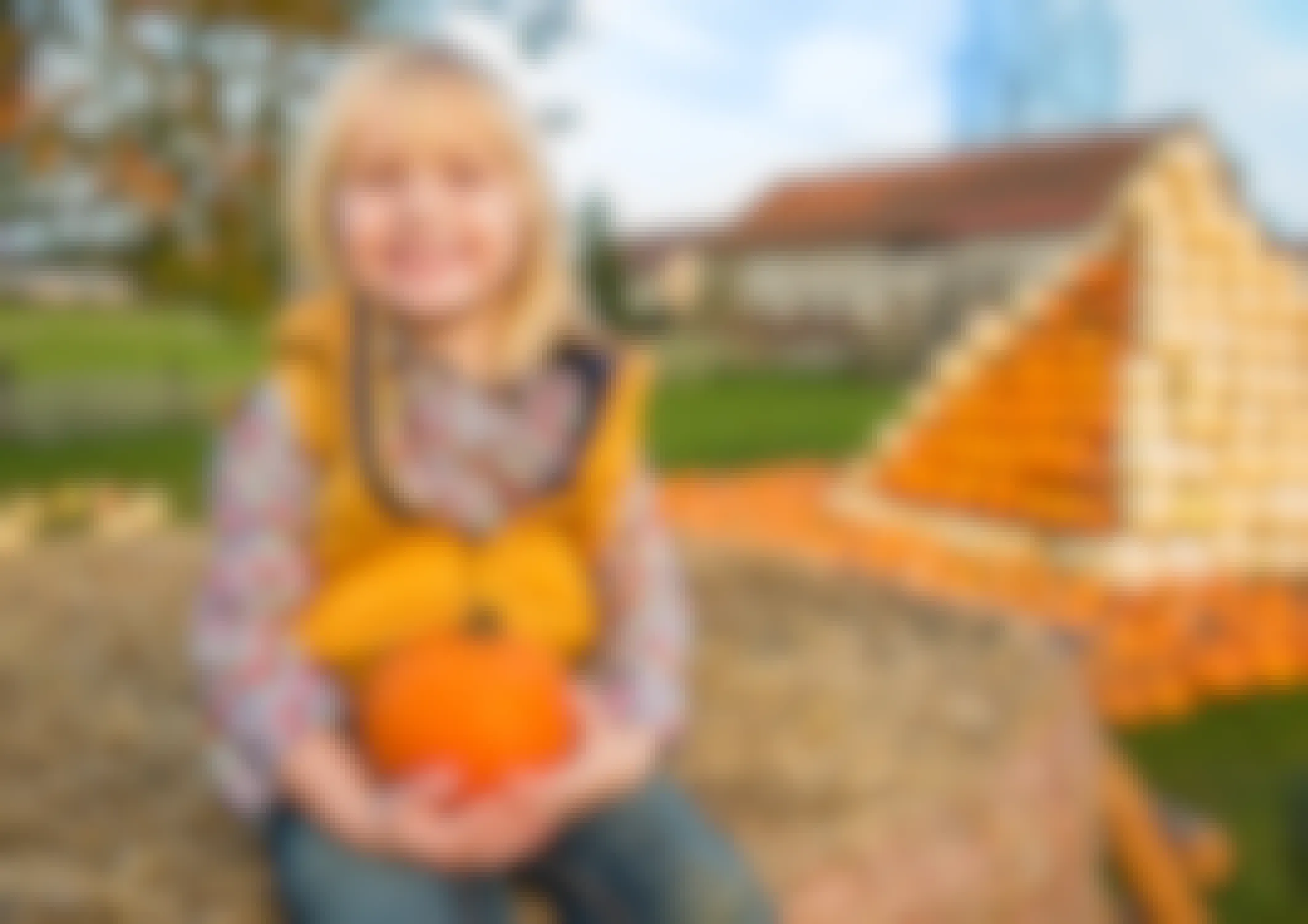 young girl holding pumpkin at patch
