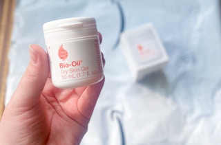 hand holding a container of bio-oil dry skin oil over an amazon envelope