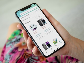 A person holding a phone displaying the Coupons page in the Amazon mobile app.