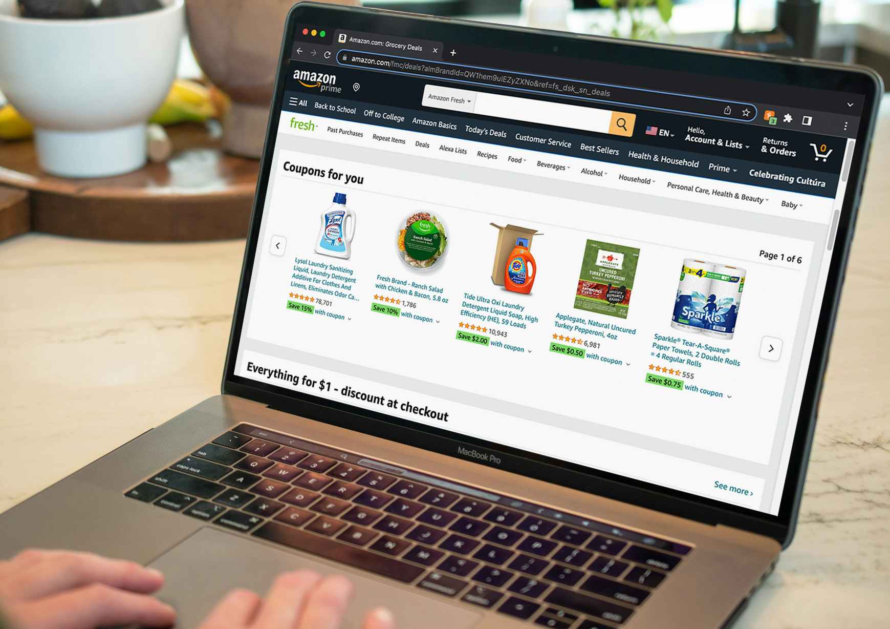 A person using a laptop displaying Amazon Fresh coupons available.