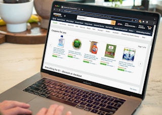 A person using a laptop displaying Amazon Fresh coupons available.