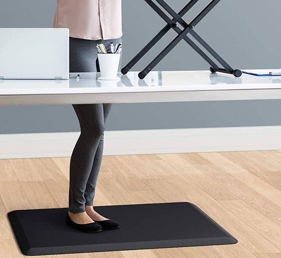 A woman working at a desk standing on a mat.