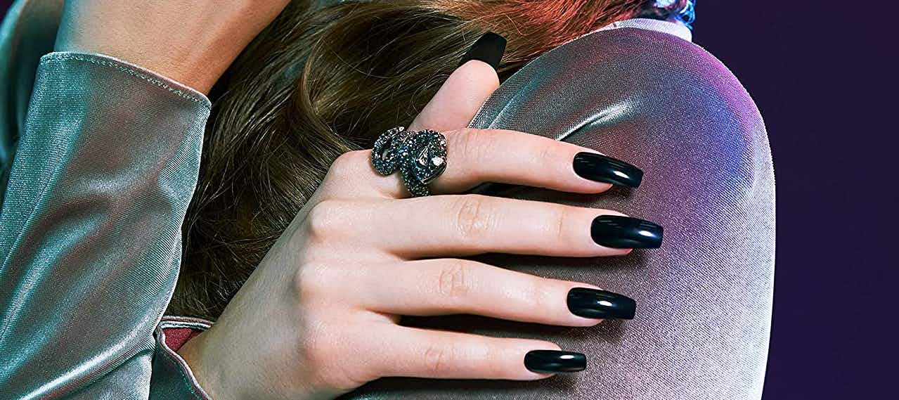 a hand with a ring wearing long black nails