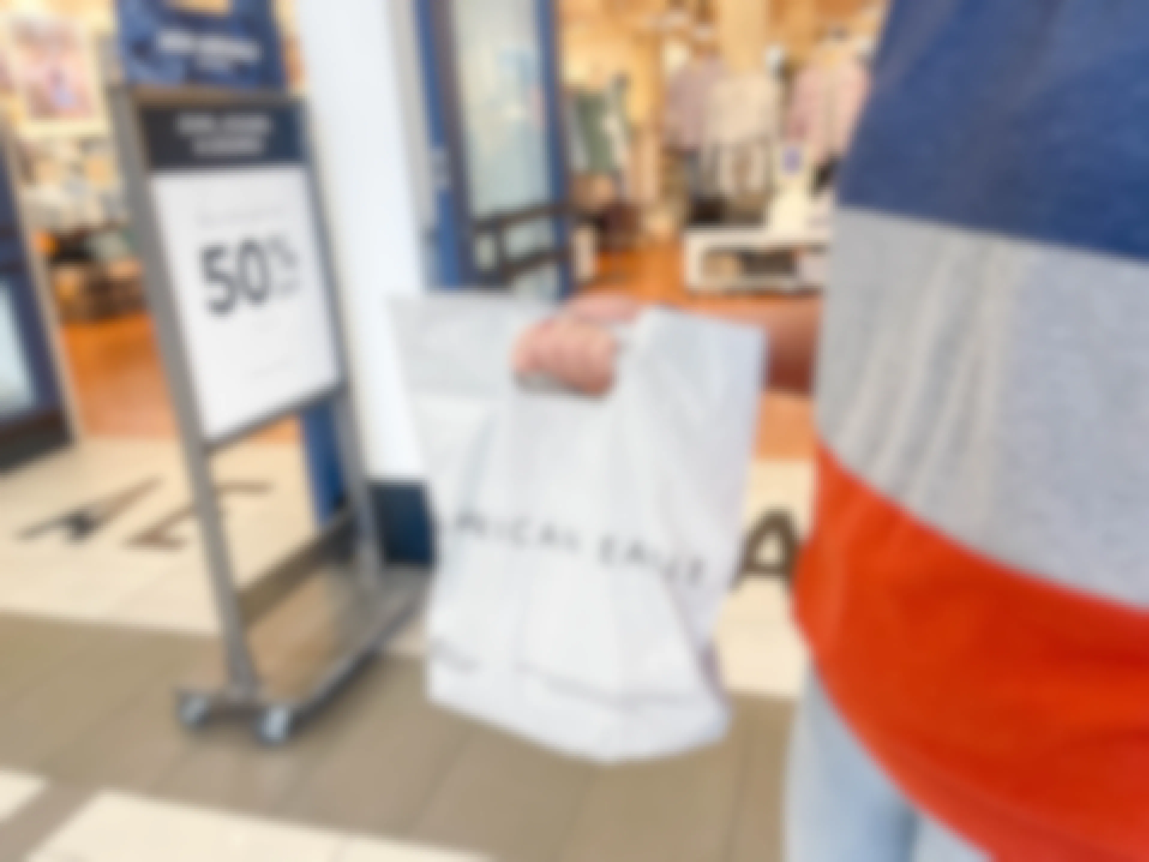 a woman holding an american eagle bag outside store