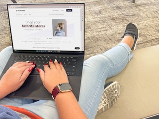 person with a laptop sitting on couch with american eagle page on shop runner website