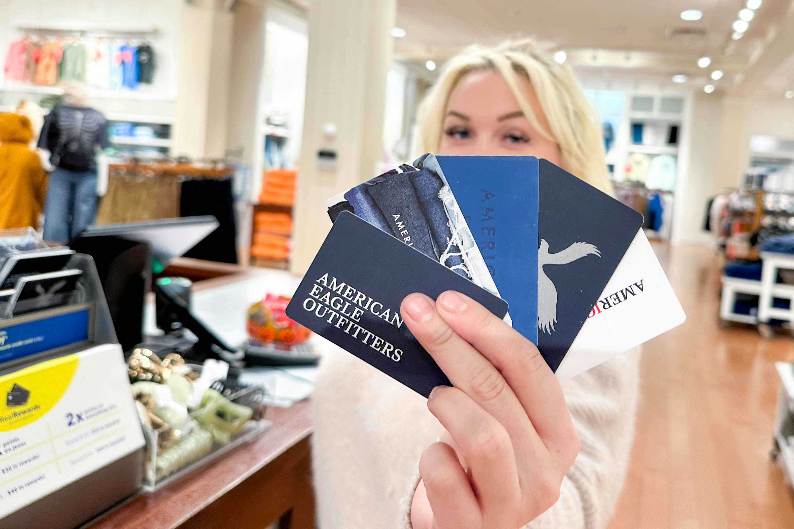 a person holding up american eagle gift cards 
