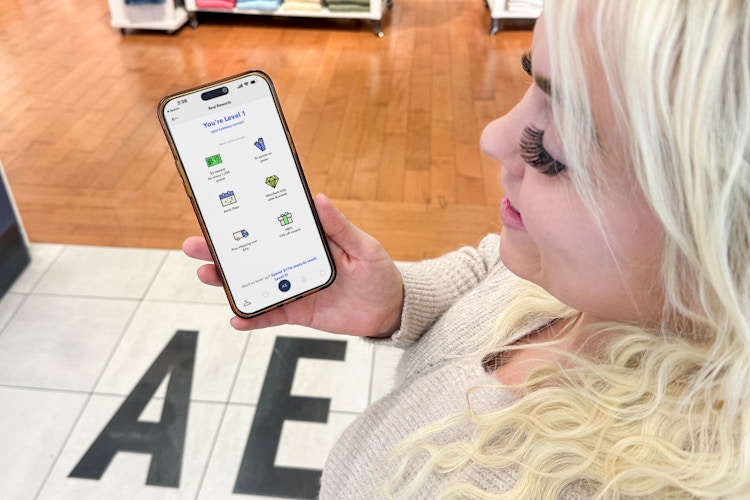 a woman holding a phone outside the american eagle store
