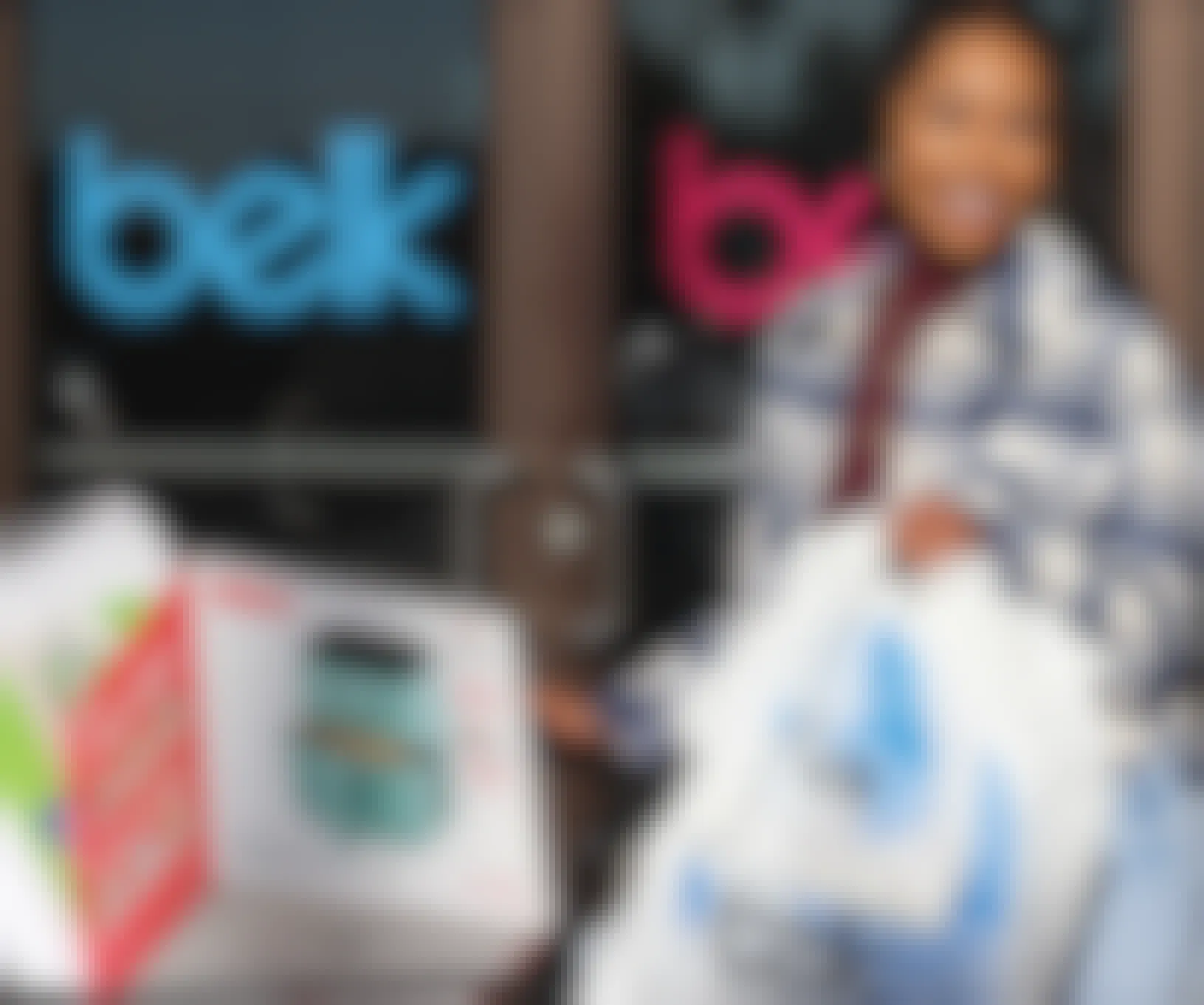 A customer leaving a Belk store carrying Belk bags and pushing a cart full of purchased items.