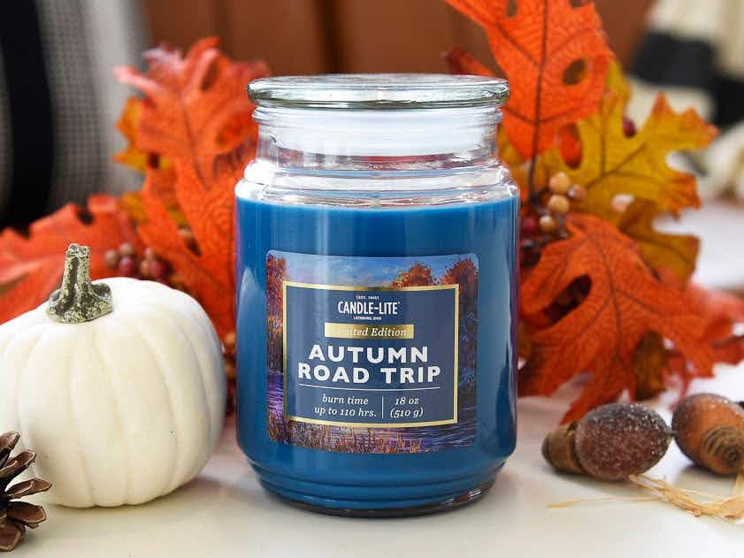 An Autumn Road Trip Candle-lite candle on a table with fall decorations.