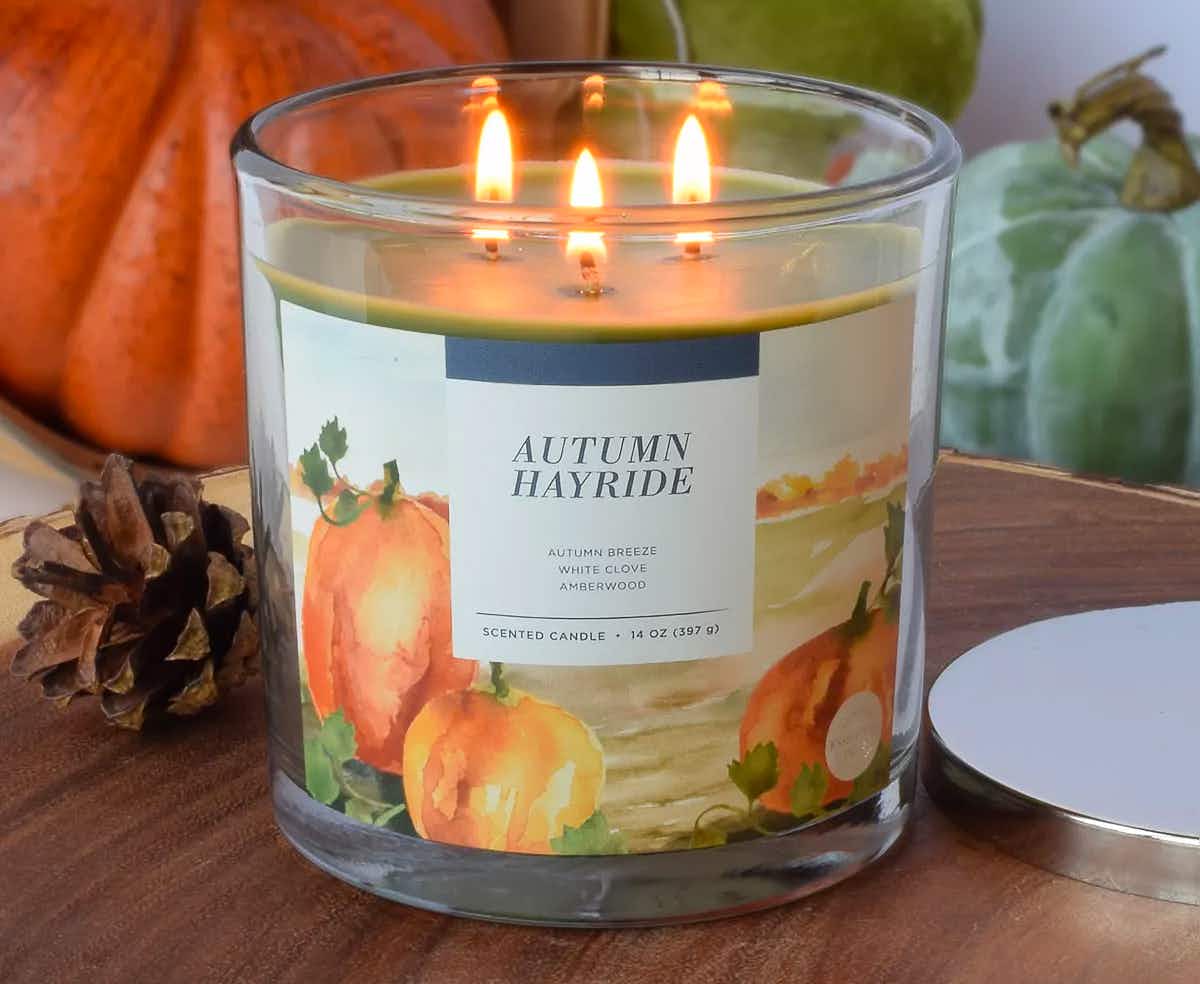 An Autumn Hayride Sonoma candle from Kohl's on a table with fall decorations.