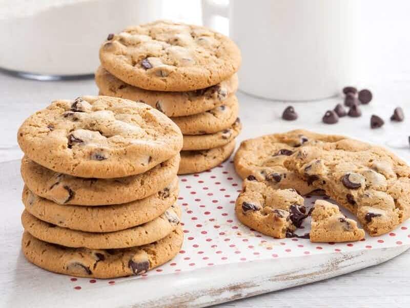 Stacks of Mrs. Fields cookies on a tray sitting on a kitchen counter.