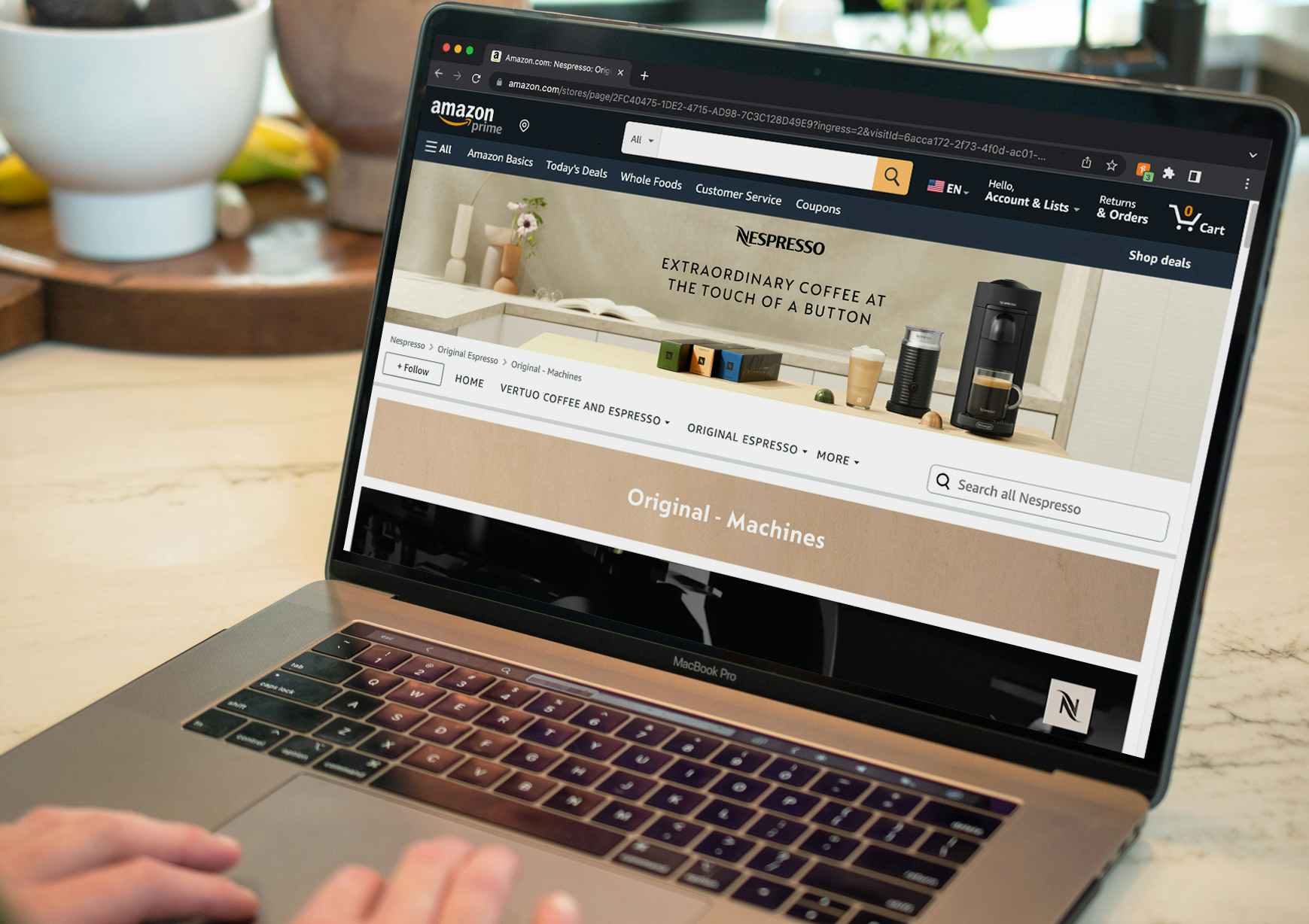 A person using a laptop displaying the Nespresso store page on Amazon.