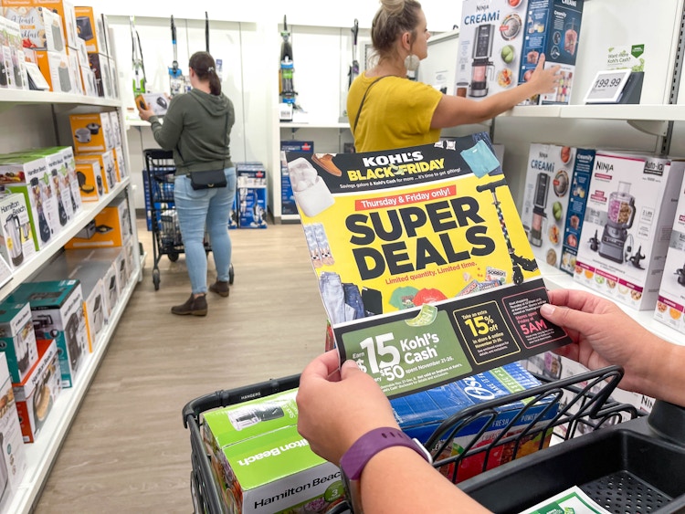 People shopping in the appliance section of Kohl's, one person holding a Black Friday ad.