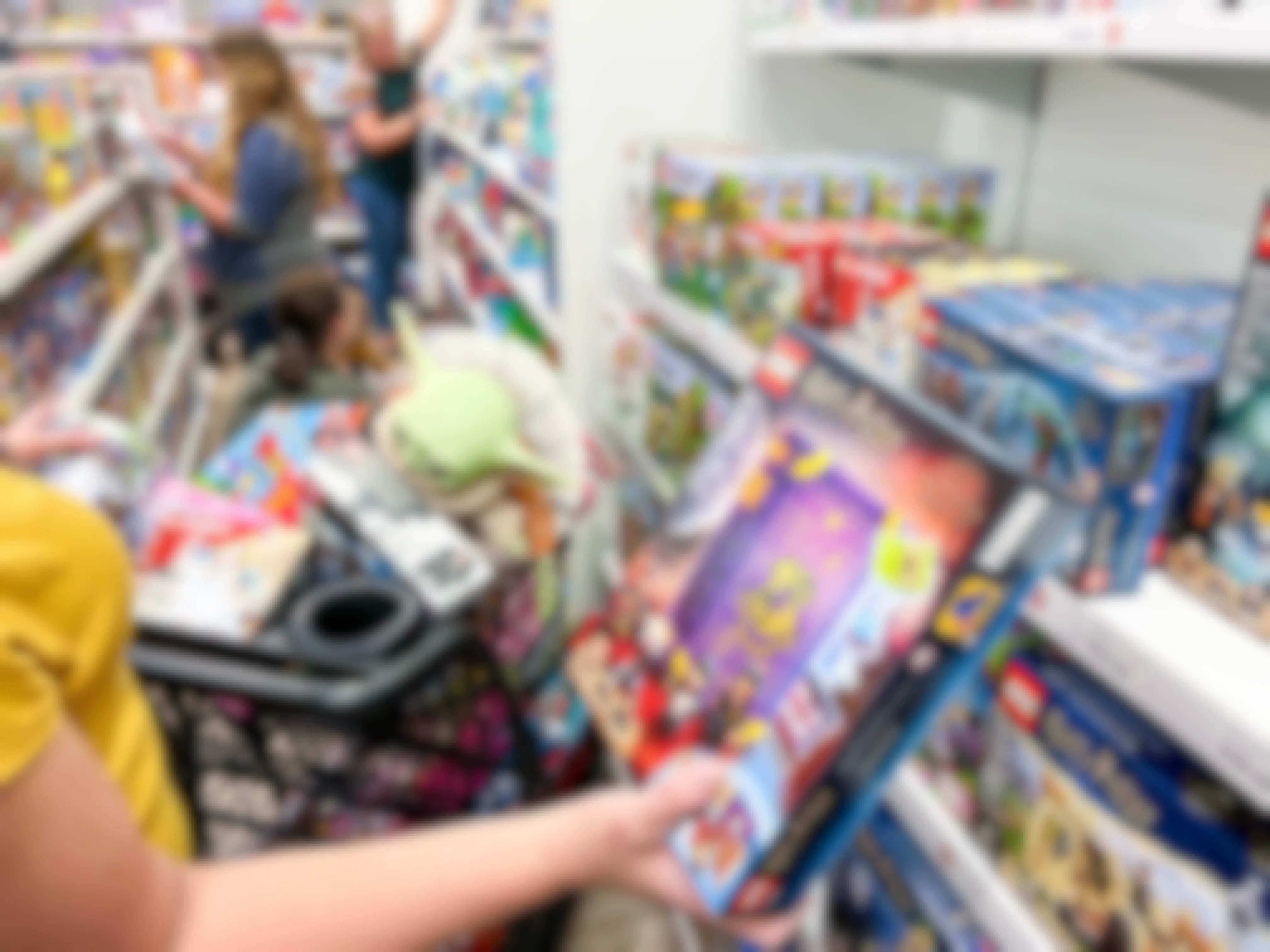 a woman holding a harry potter lego set in a busy kohl's toy aisle.