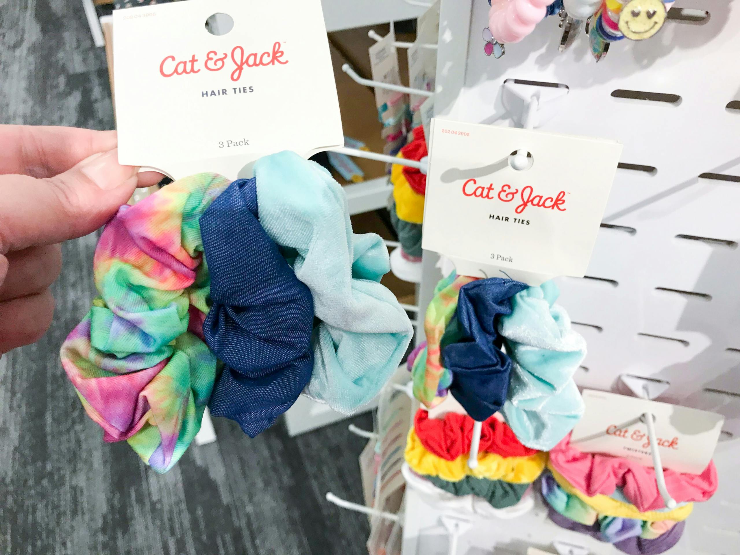 hand holding scrunchies in front of shelves with more scrunchies