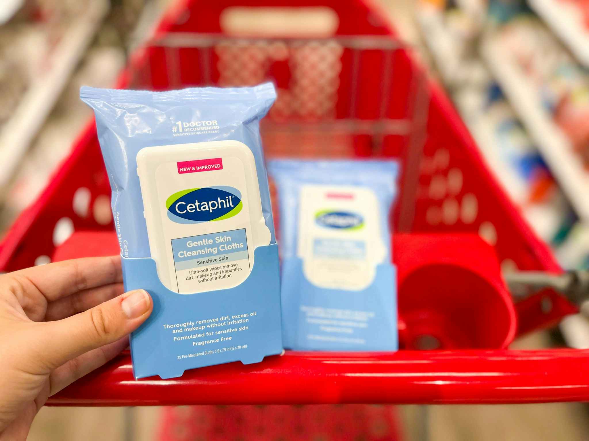 hand holding pack of cetaphil wipes in front of target cart with more wipes inside