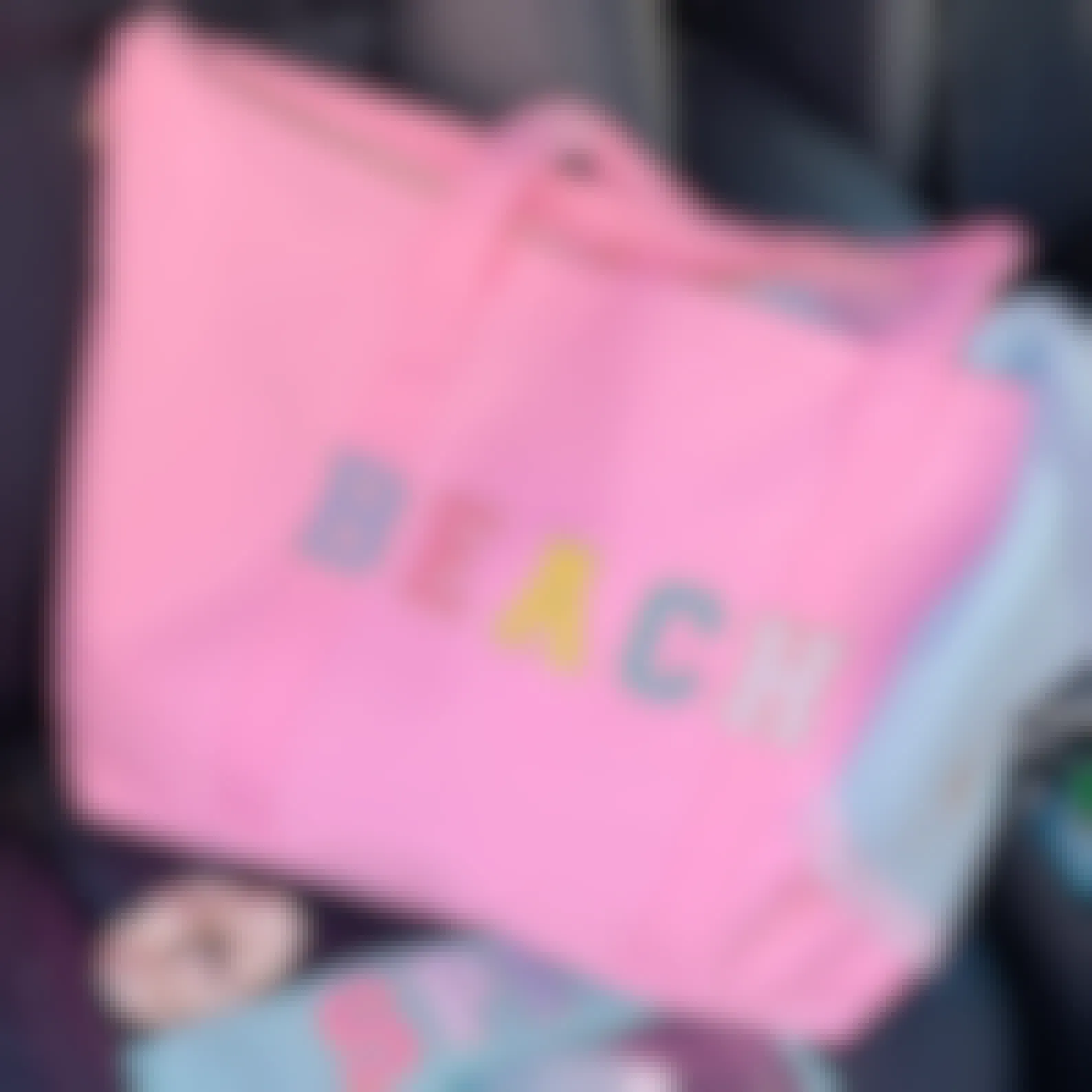 A tote bag that says "Beach" on the front in custom patches sitting in the passenger seat of a vehicle.