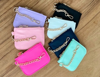 Different colored chained wallets sitting together on a wooden table.