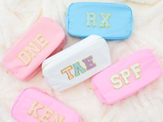 Nylon pouches customized with patches in a pile on a marble counter.