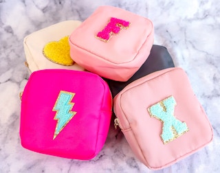 Nylon pouches customized with patches in a pile on a marble counter.