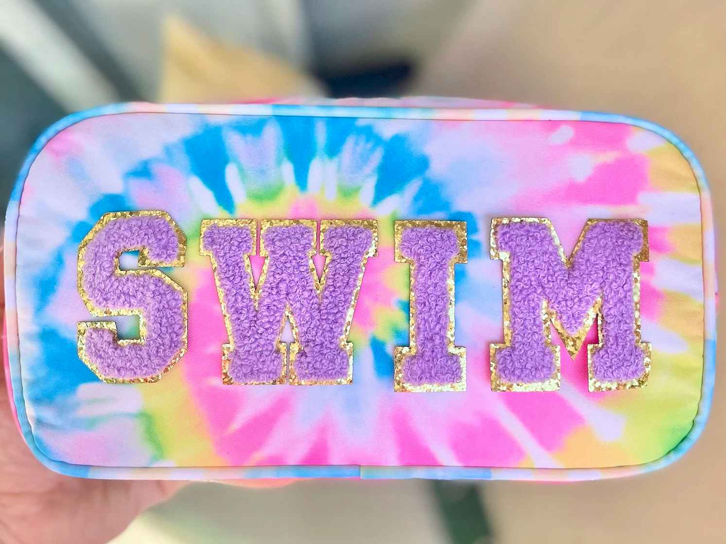 A custom tie-dye pouch with the word "swim" on the front in patches.