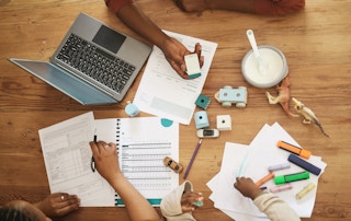 parents and children at table with bills, laptop, and toys
