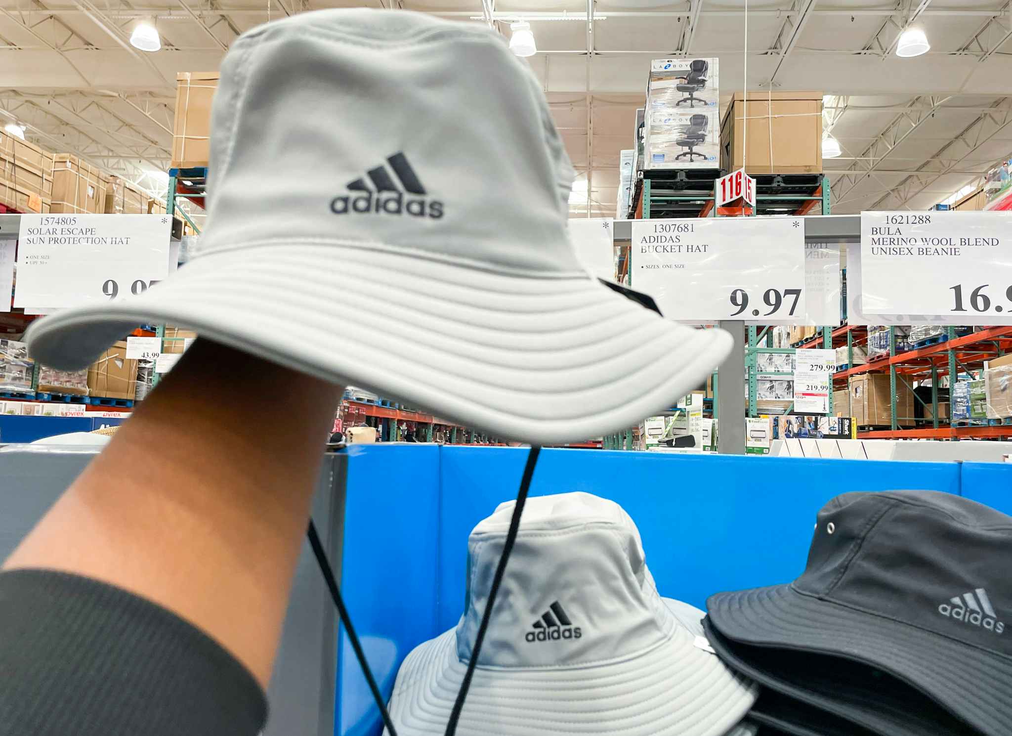 bucket hat hand held near sale sign at costco
