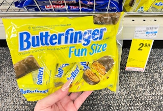 hand holding fun size bag of butterfinger next to sale tag