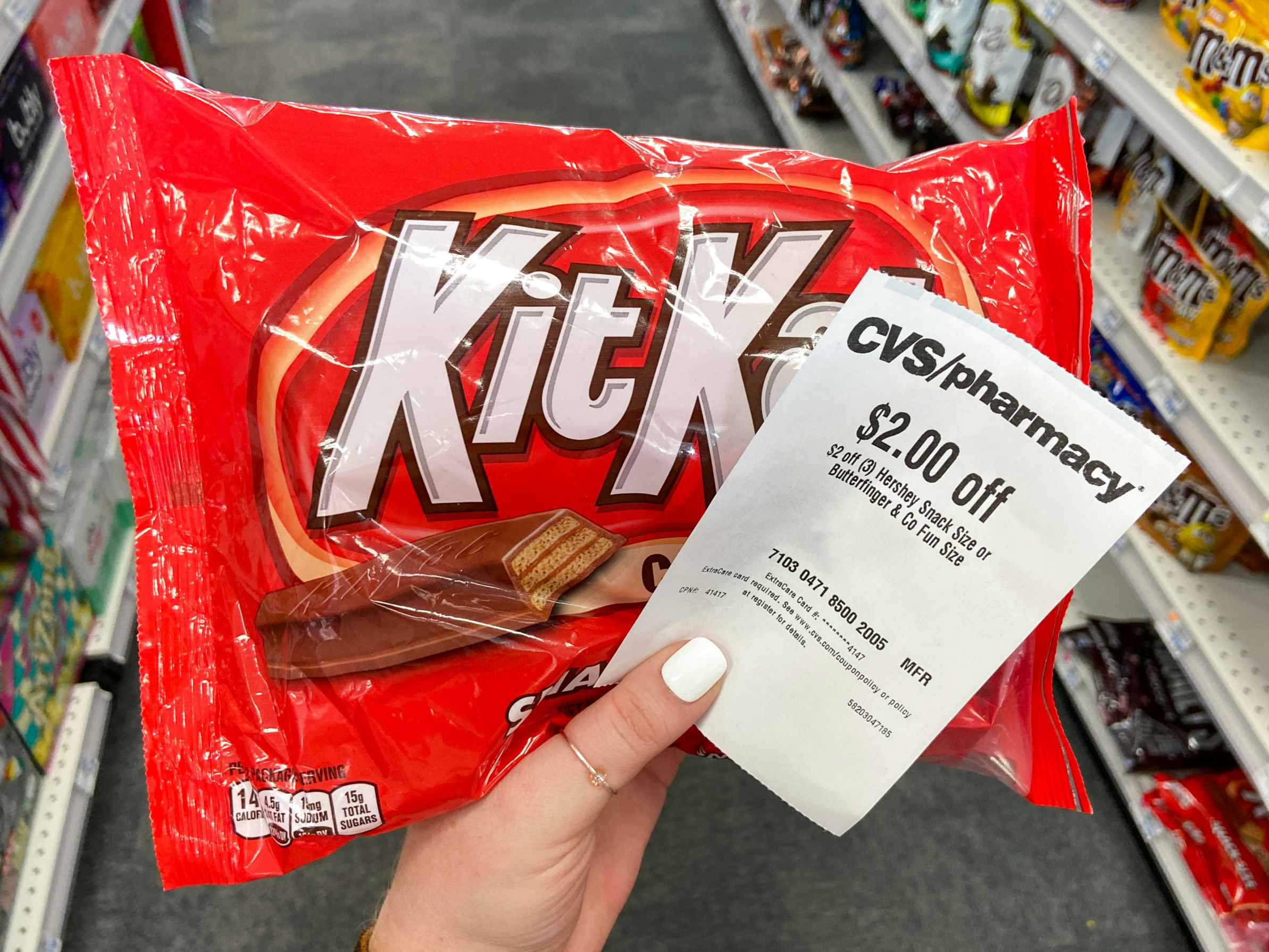 a hand holding up a bag of kit kats with a coupon