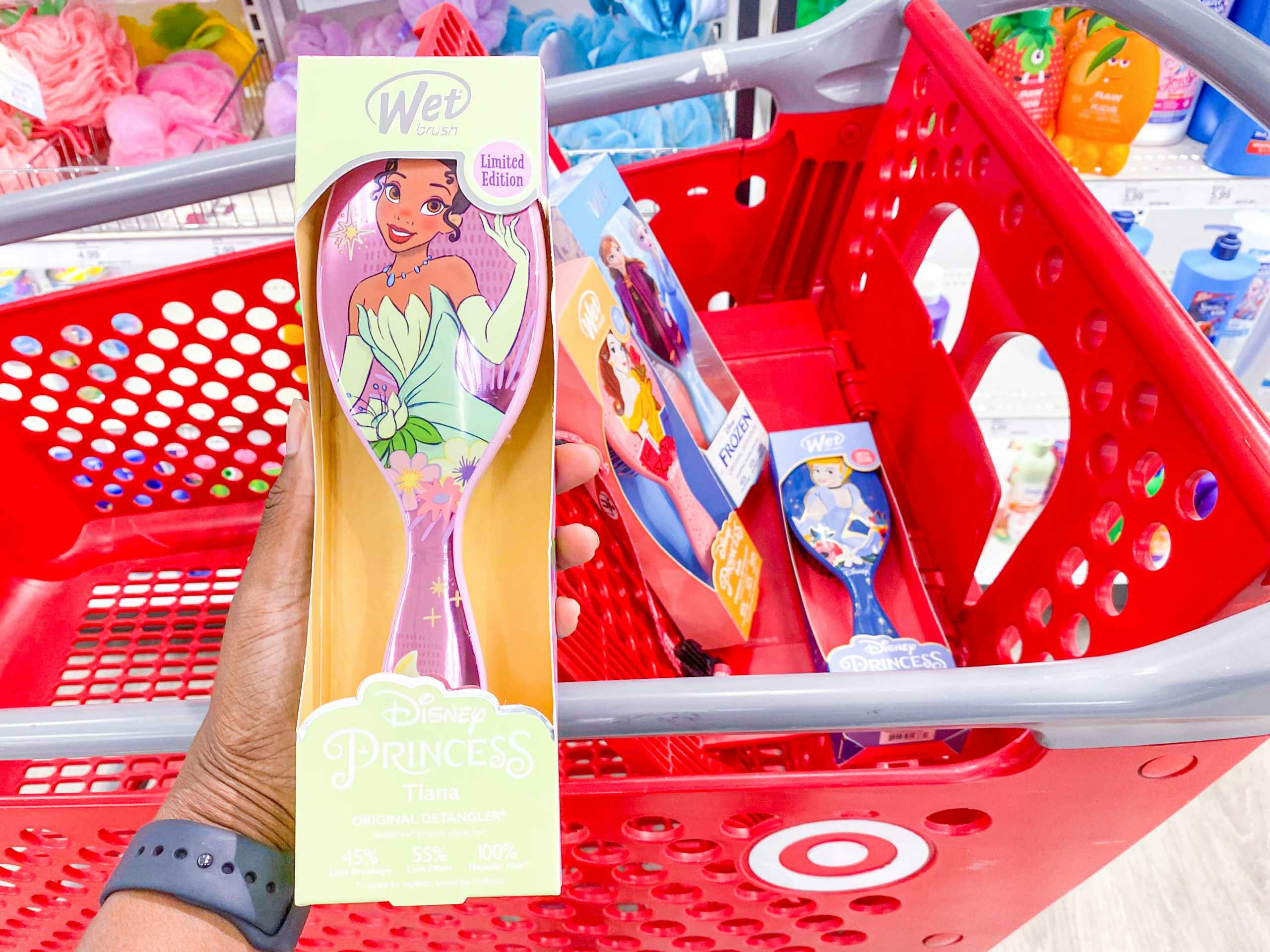 hand holding disney princess brush in front of target cart with disney princess wet brushes inside