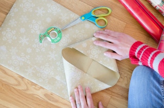 A person folding in wrapping paper to make the bottom of a diy bag.