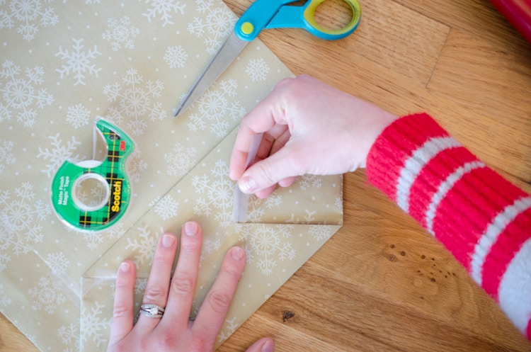 A person using tape to secure the bottom of a DIY wrapping paper bag.