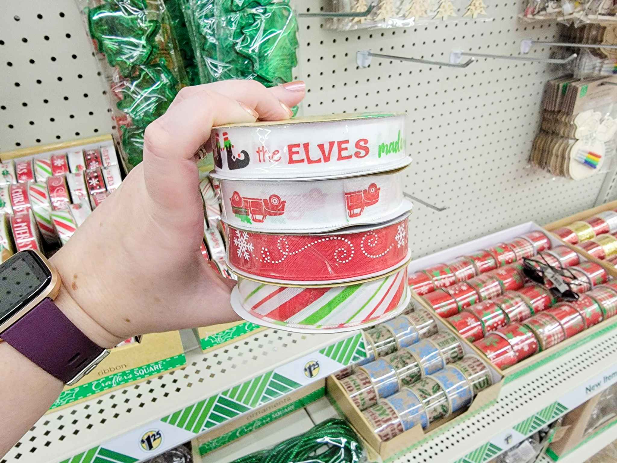 hand holding 4 rolls of christmas ribbon