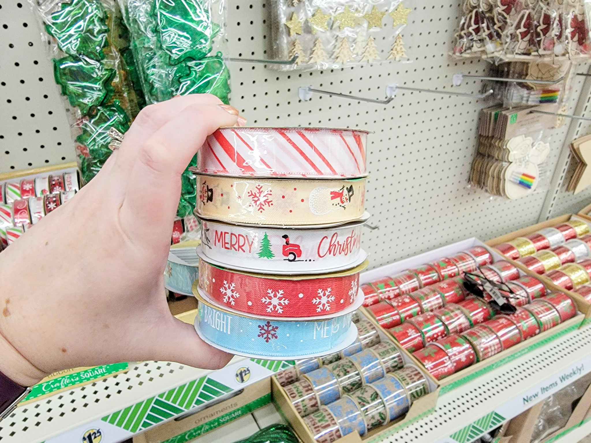 hand holding 5 rolls of christmas ribbon