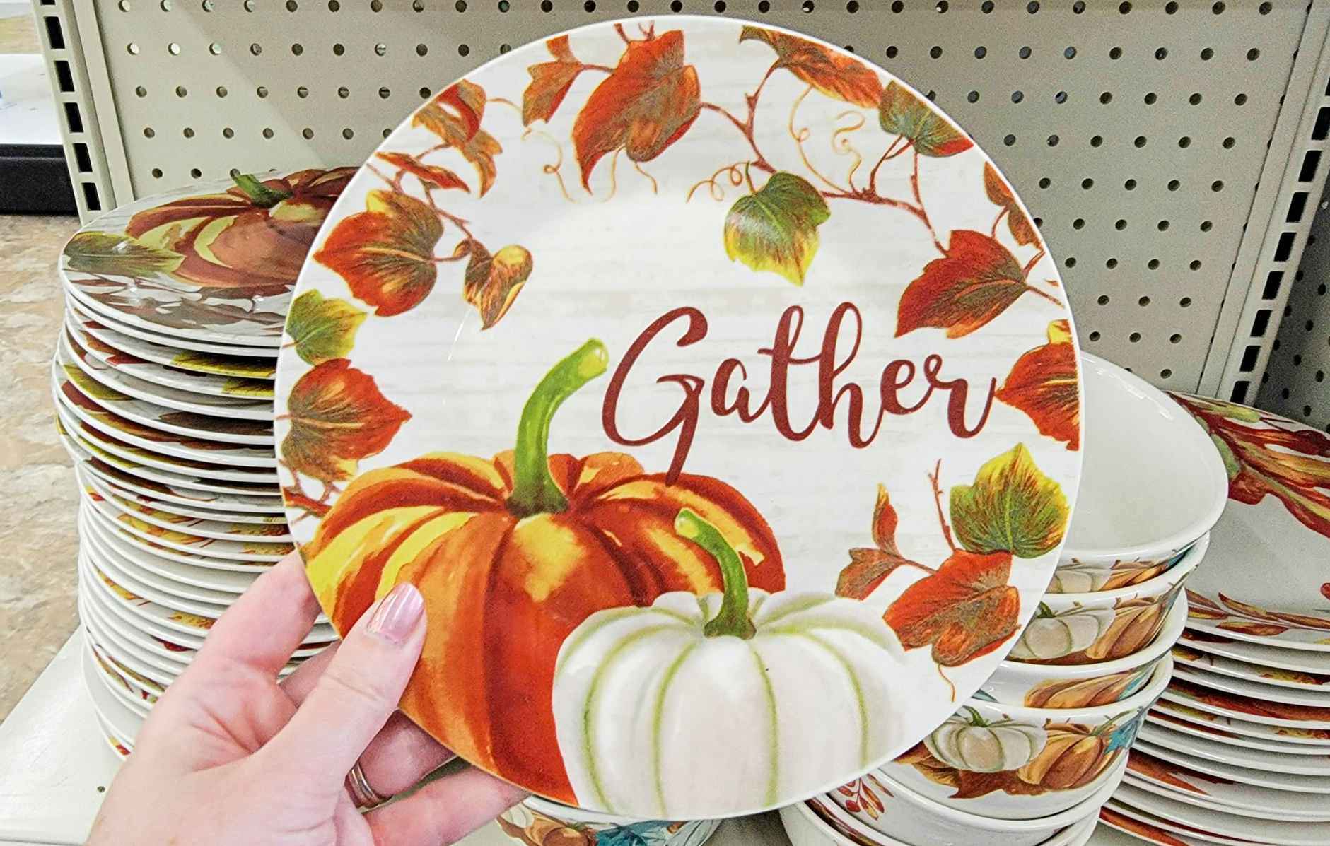 hand holding a small dish that says gather with pumpkins on it
