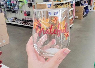hand holding a glass with leaves that says grateful on it