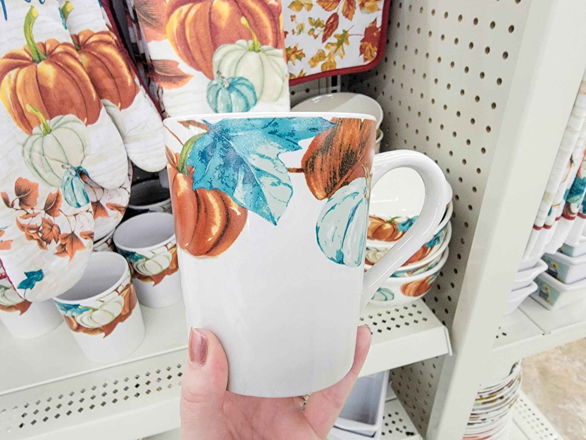 hand holding a mug with pumpkins on it