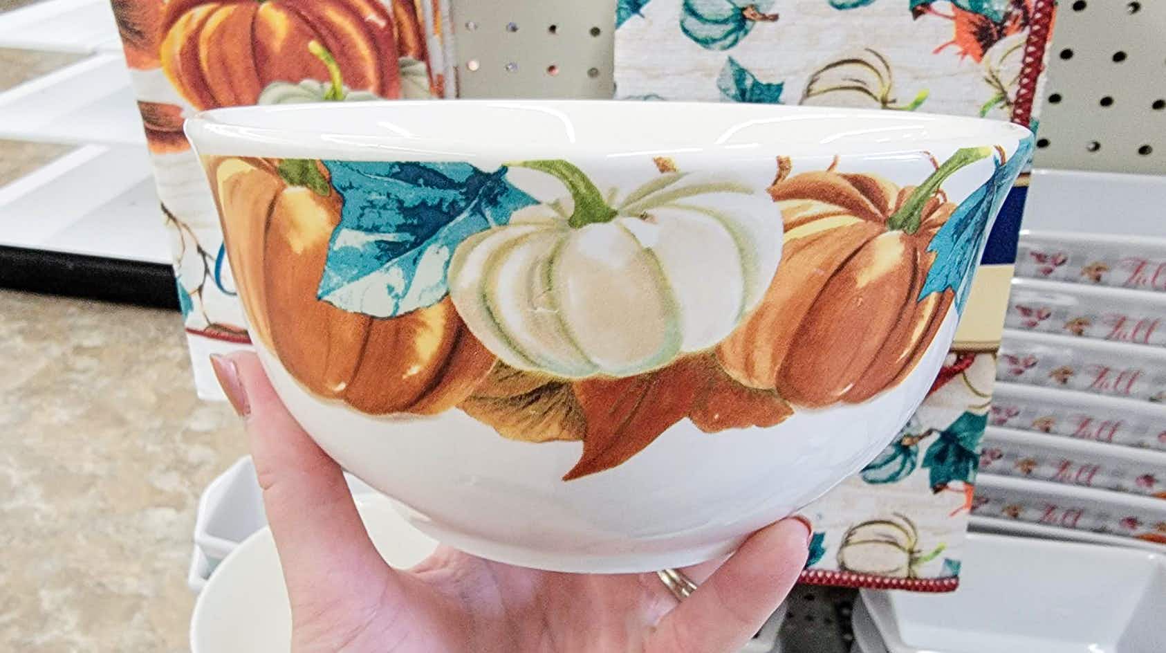 hand holding a bowl with pumpkins on it