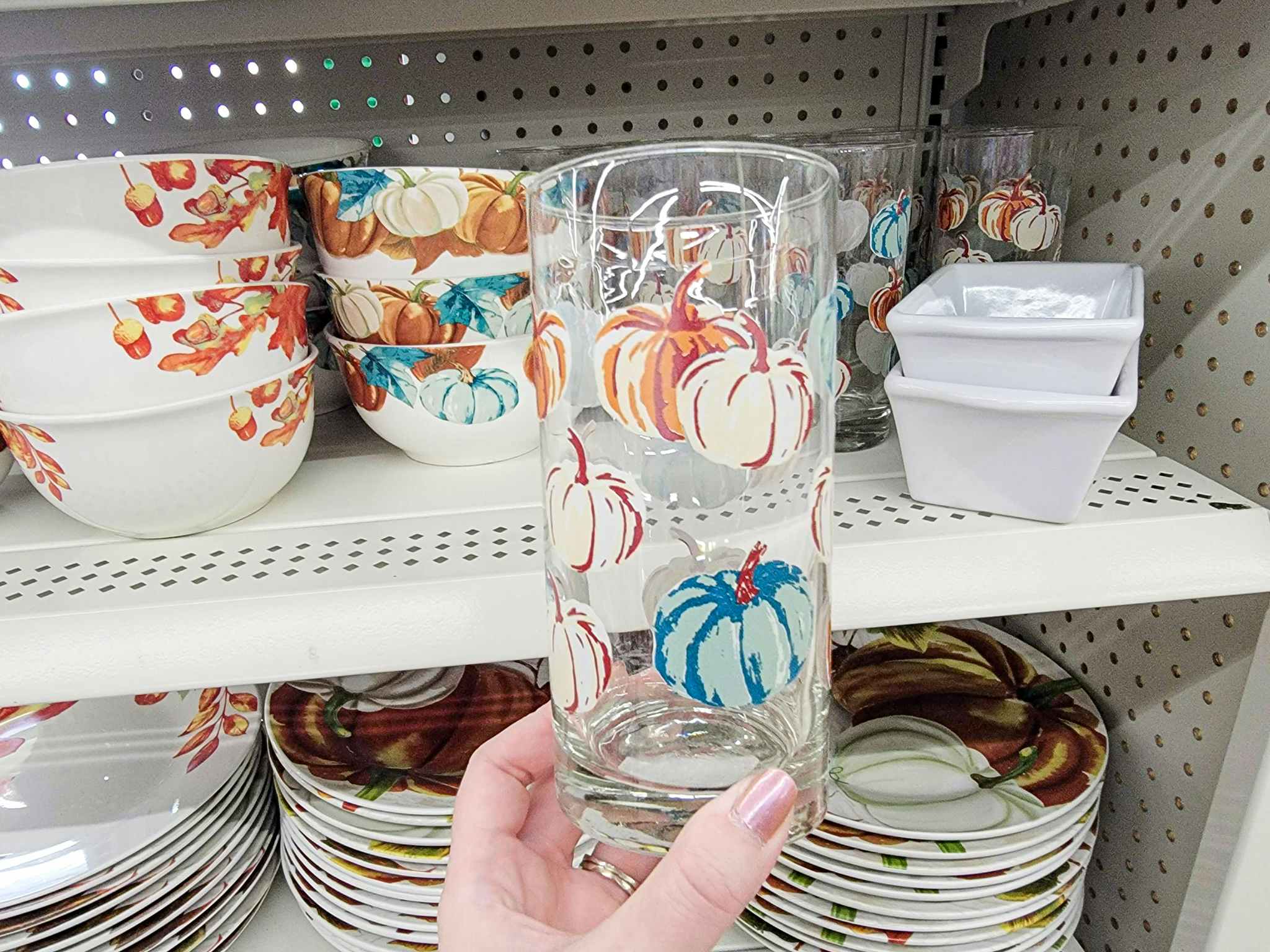 hand holding a glass with pumpkins on it