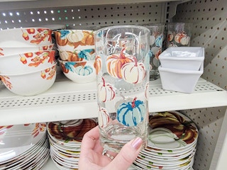 hand holding a glass with pumpkins on it