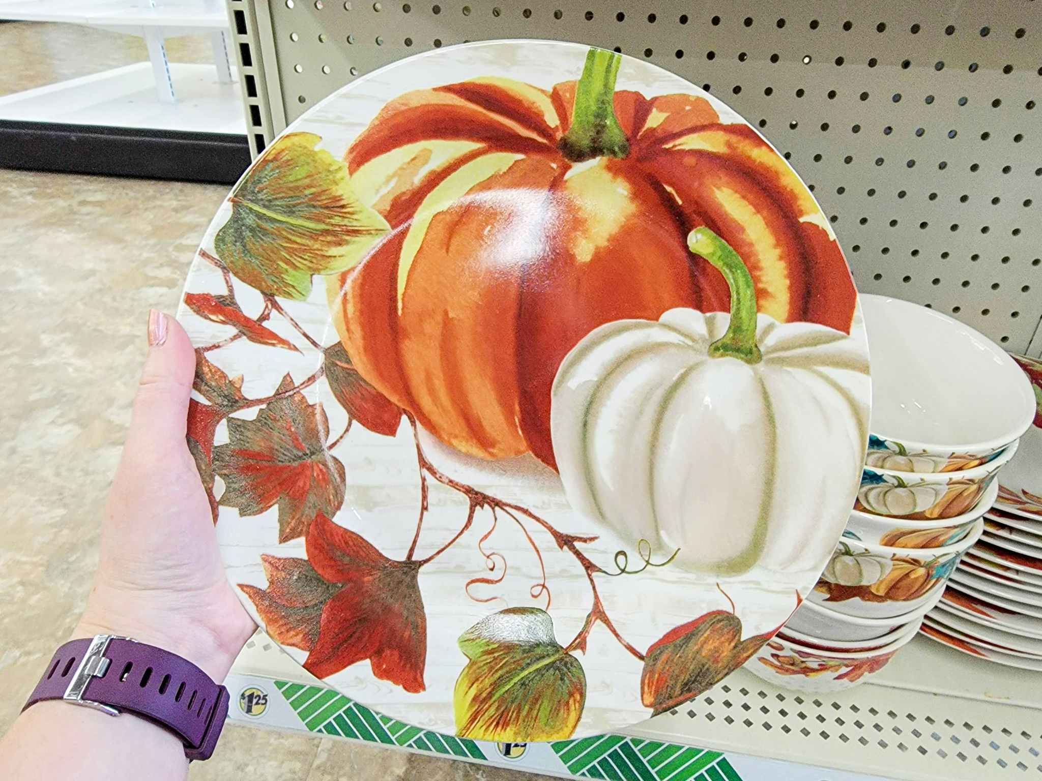hand holding a dinner plate with pumpkins on it