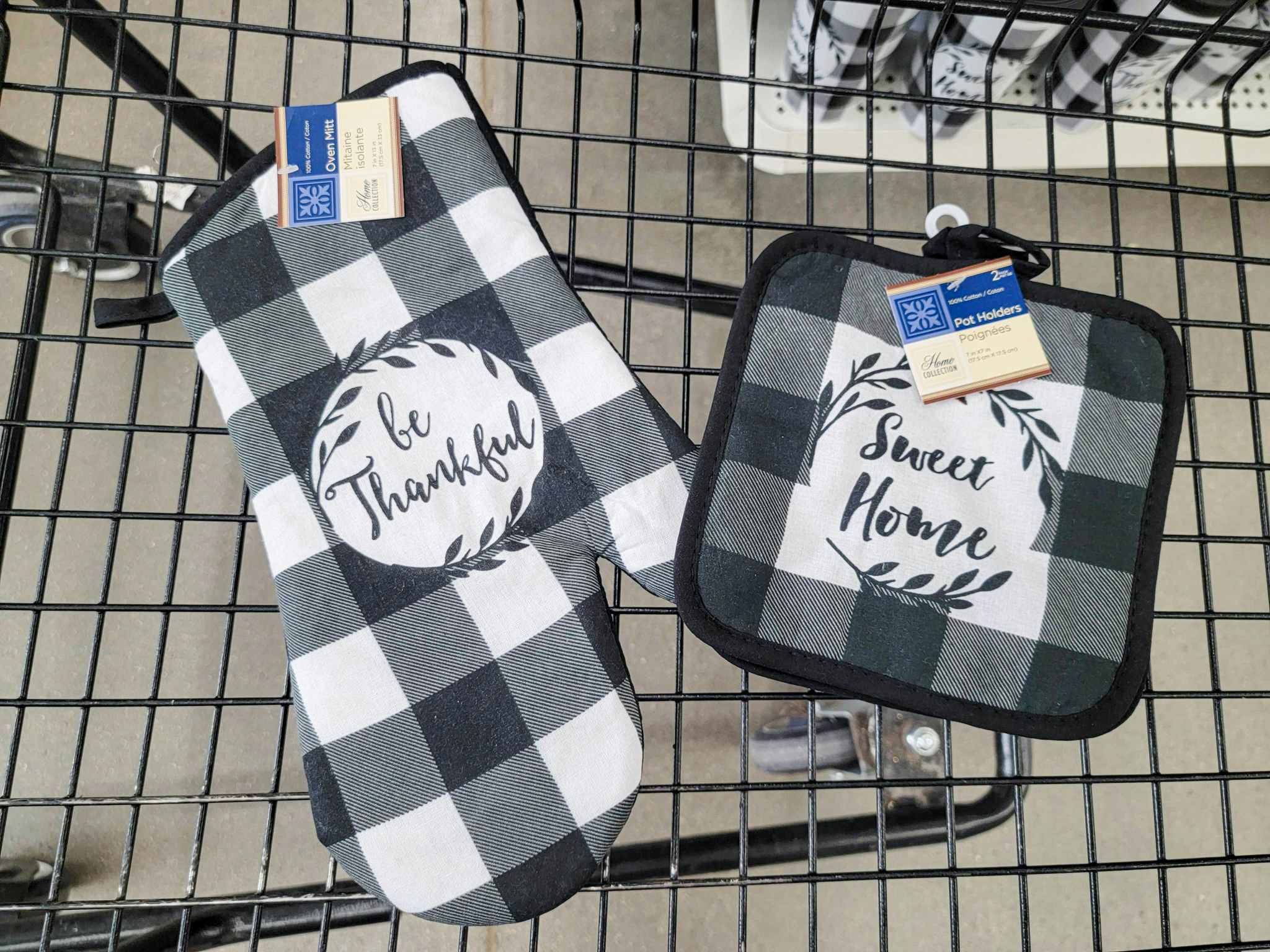 a buffalo plaid pot holder that says be thankful next to a pot holder that says sweet home in a cart